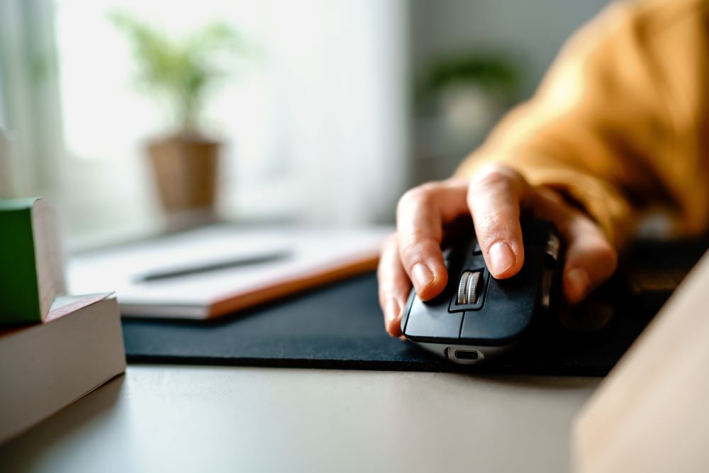 Close up shot of a hand using a computer mouse on table